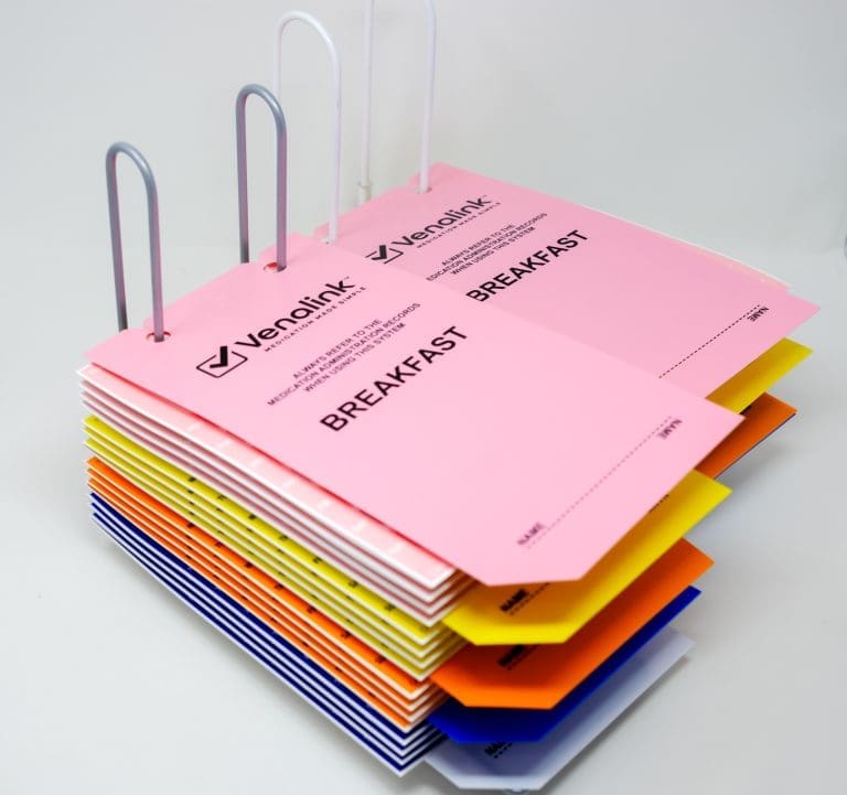 Two racks full of monitored dosage cards with white, blue, orange, yellow and pink dividers and cards. Pink breakfast dividers are at the top of both racks.