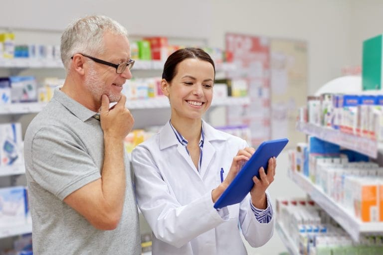 A pharmacist in the pharmacy consults with a patient using a tablet