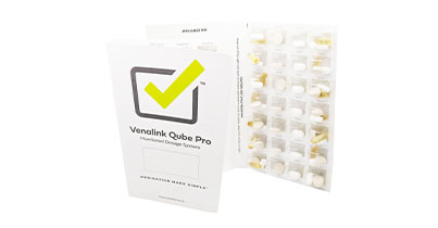 Two filled monitored dosage cards containing various tablets and capsules.