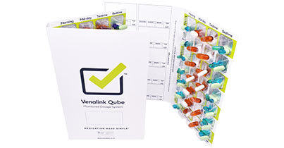 Two filled monitored dosage cards containing various tablets and capsules.