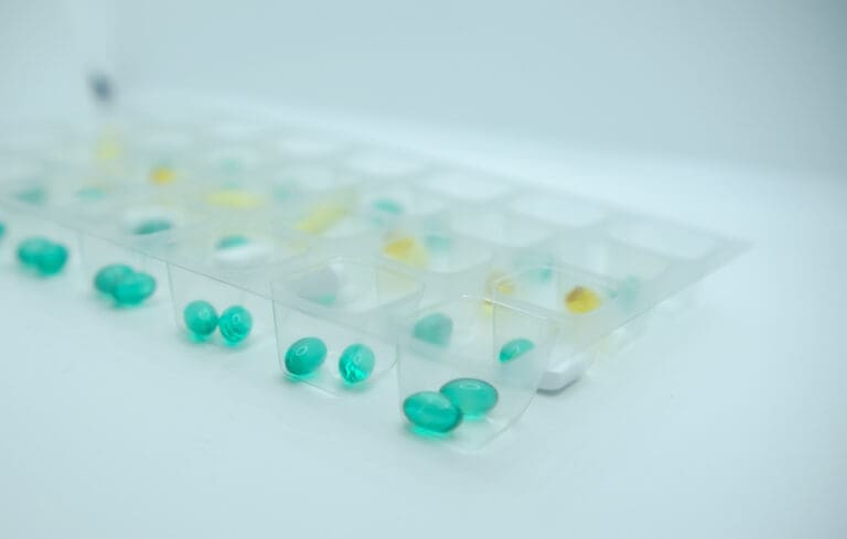 Close-up of a rPET blister pack containing green and yellow capsules, representing an eco-friendly approach with a sustainable monitored dosage system.